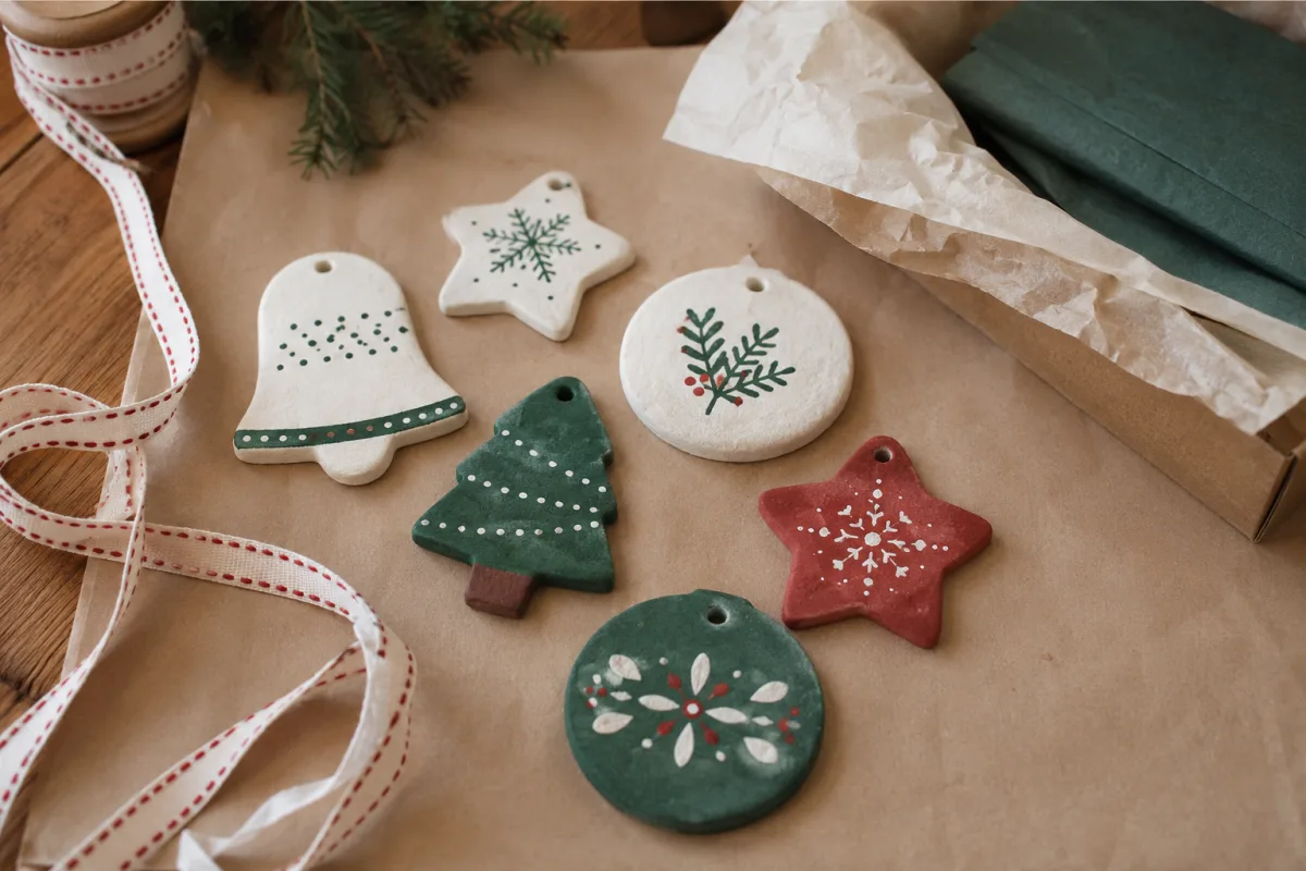 Painted salt dough ornaments drying beside ribbons and tissue paper