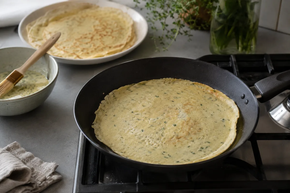 Thin savory crepe cooking in a nonstick skillet