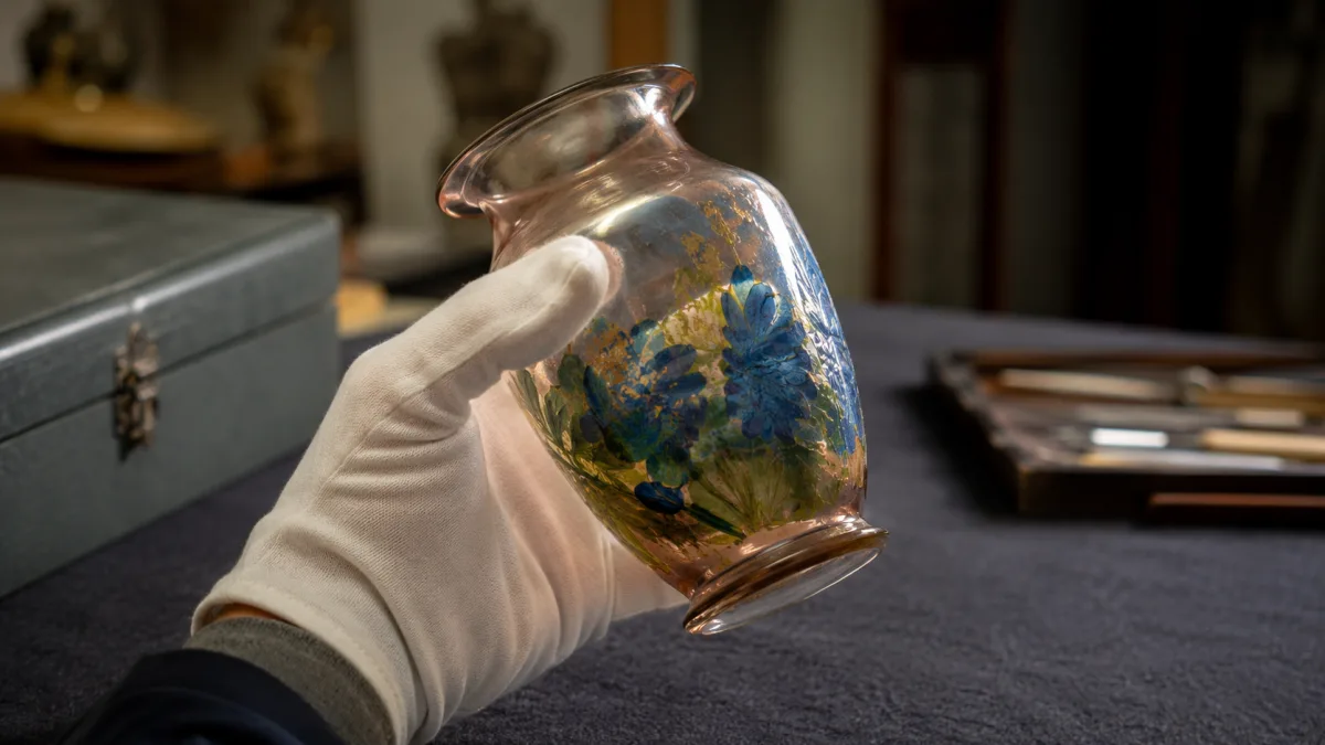 Collector inspecting the rim and base of a vintage glass vase