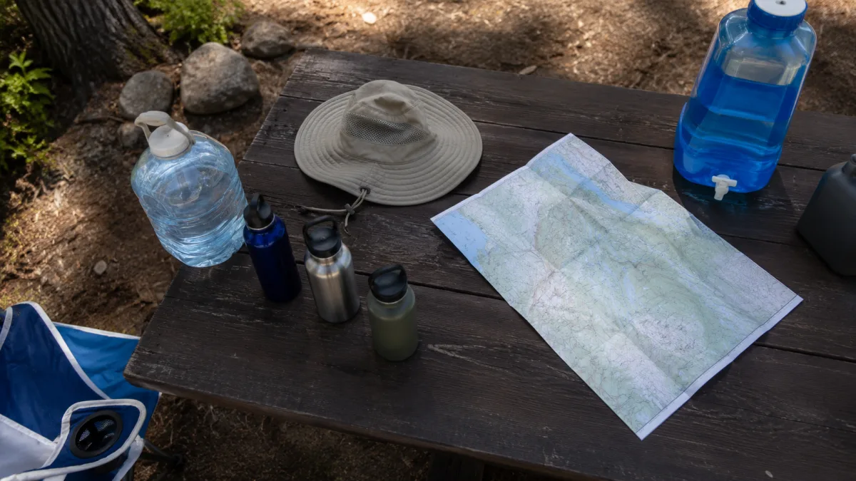 Camping water containers and sun hat on a picnic table