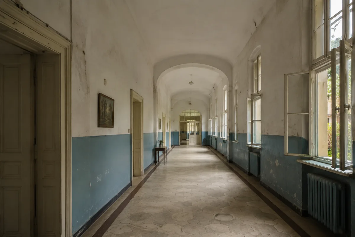 Quiet historic hospital corridor with peeling paint and soft daylight