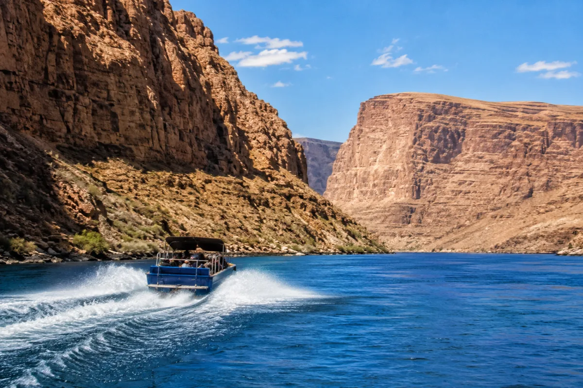 Jet boat moving along the Colorado River near desert cliffs
