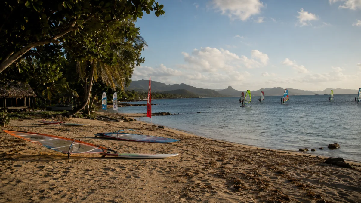 Windsurf boards and sails lined up beside a Philippine beach lagoon